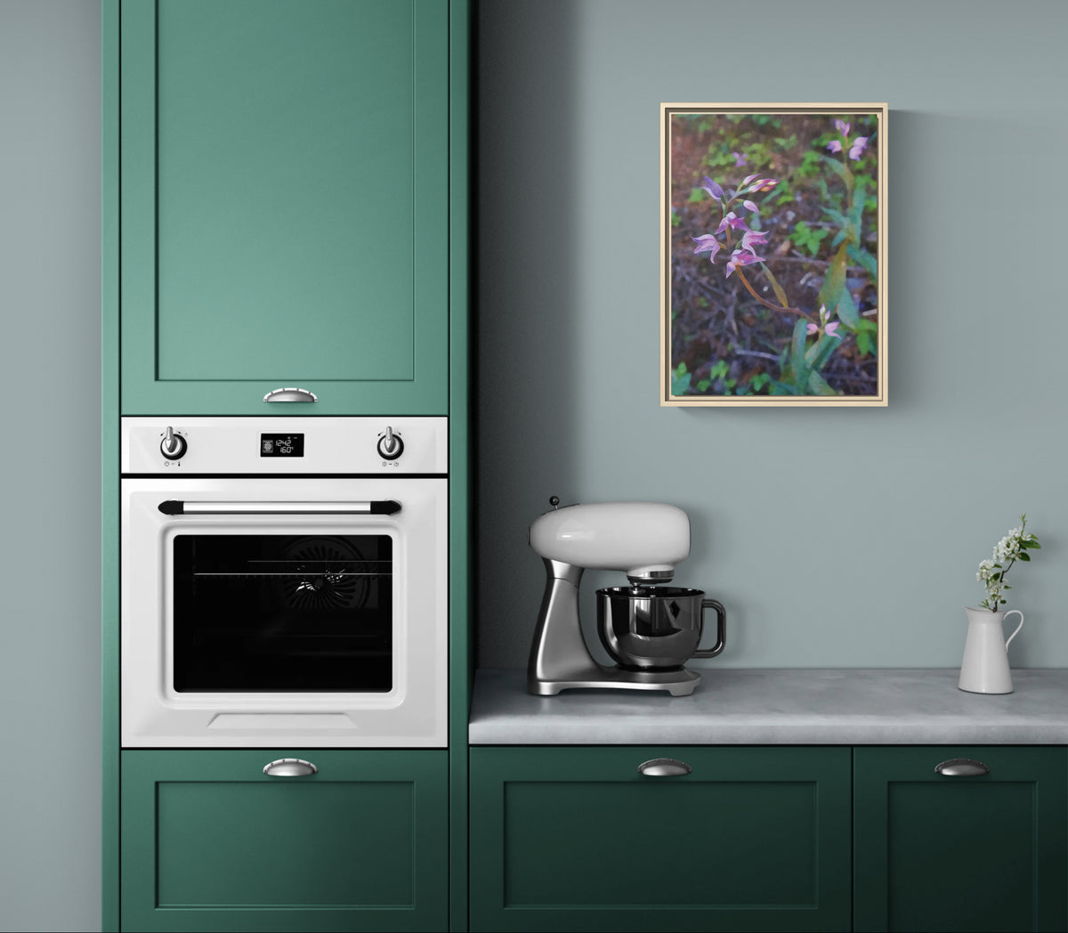 Framed floral wall art hanging in a kitchen with green cabinets and a white oven