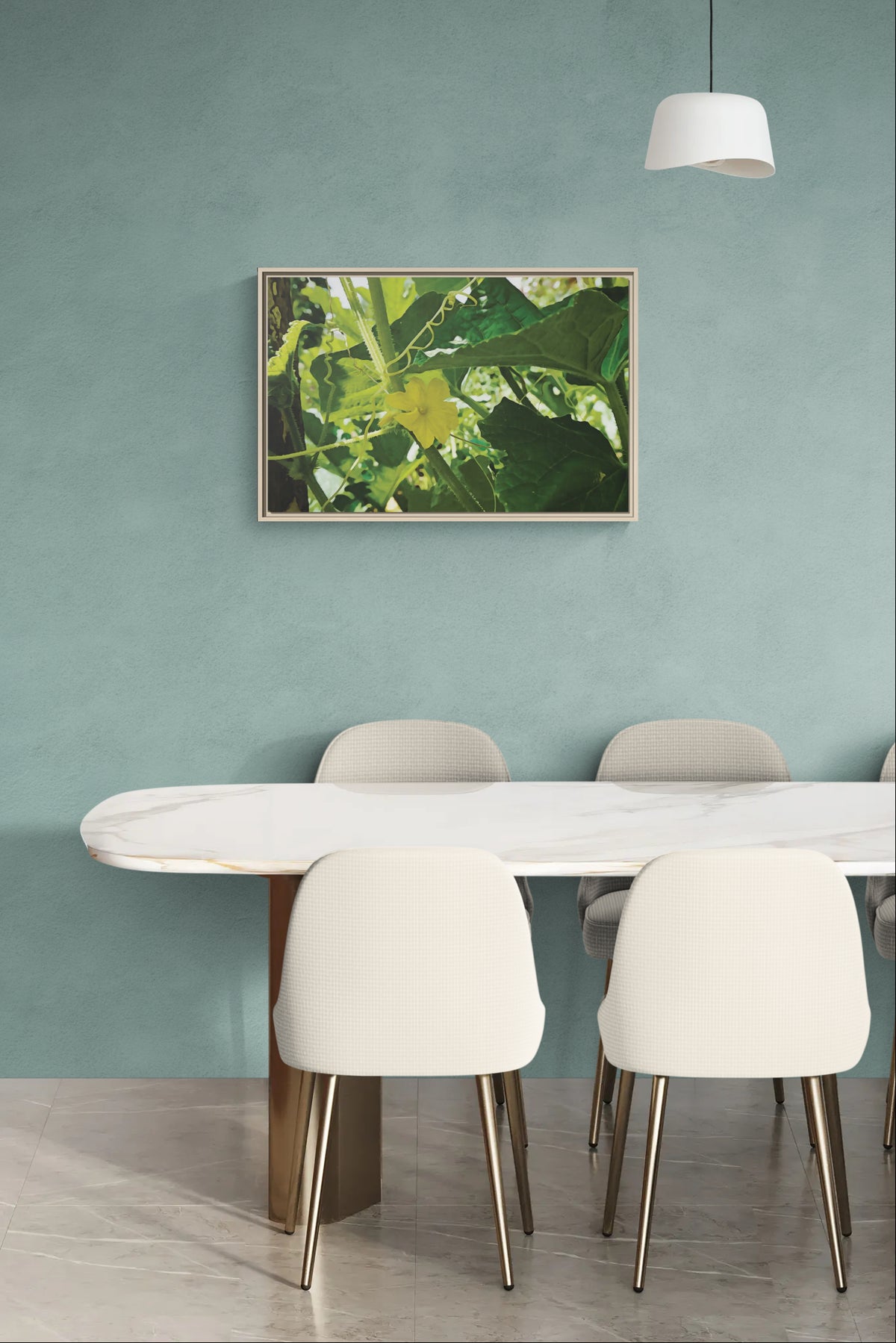 Framed botanical wall art of a yellow flower and green leaves hanging above a marble dining table