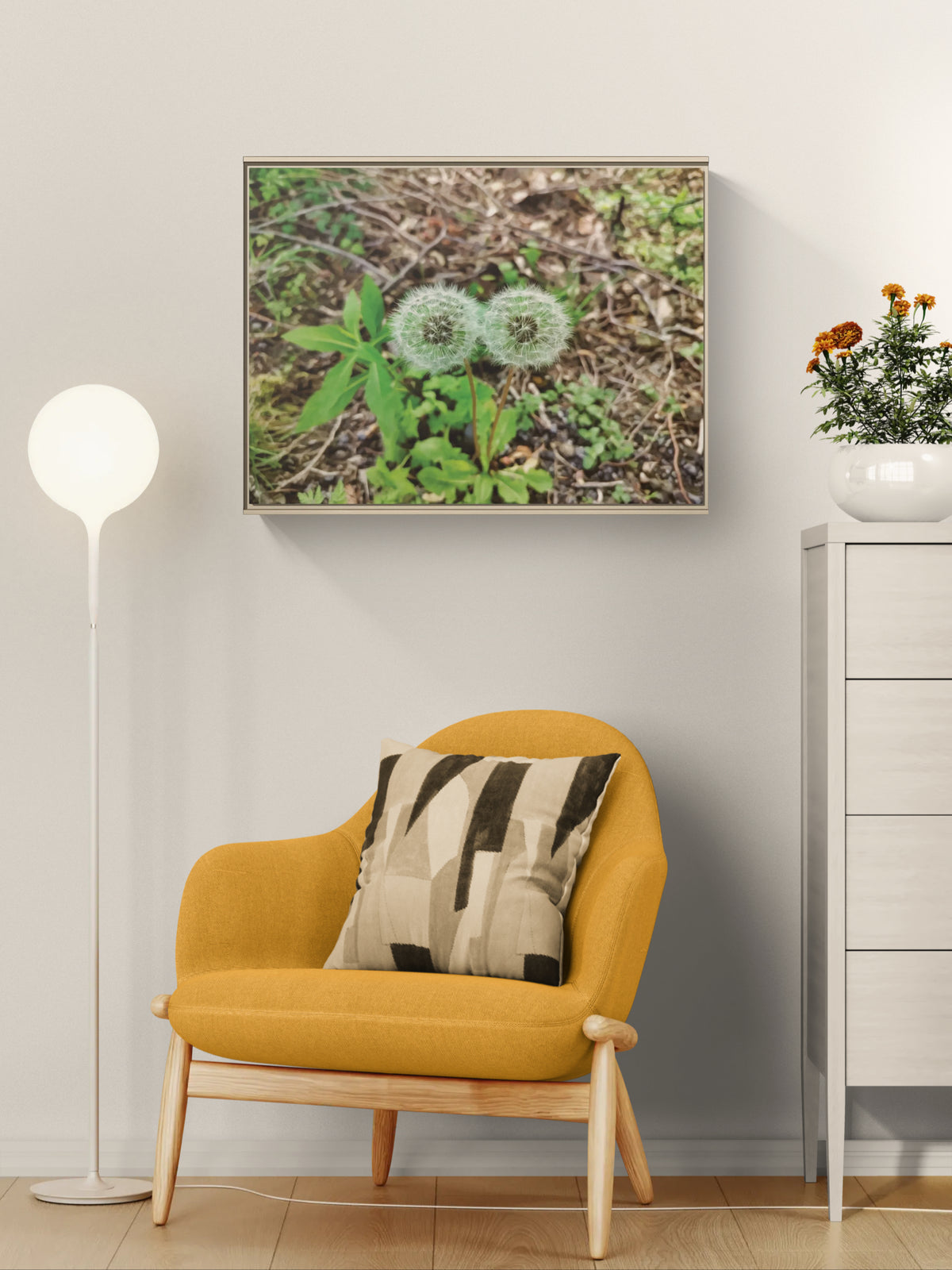 Framed wall art of two dandelion seed heads above a yellow armchair and floor lamp