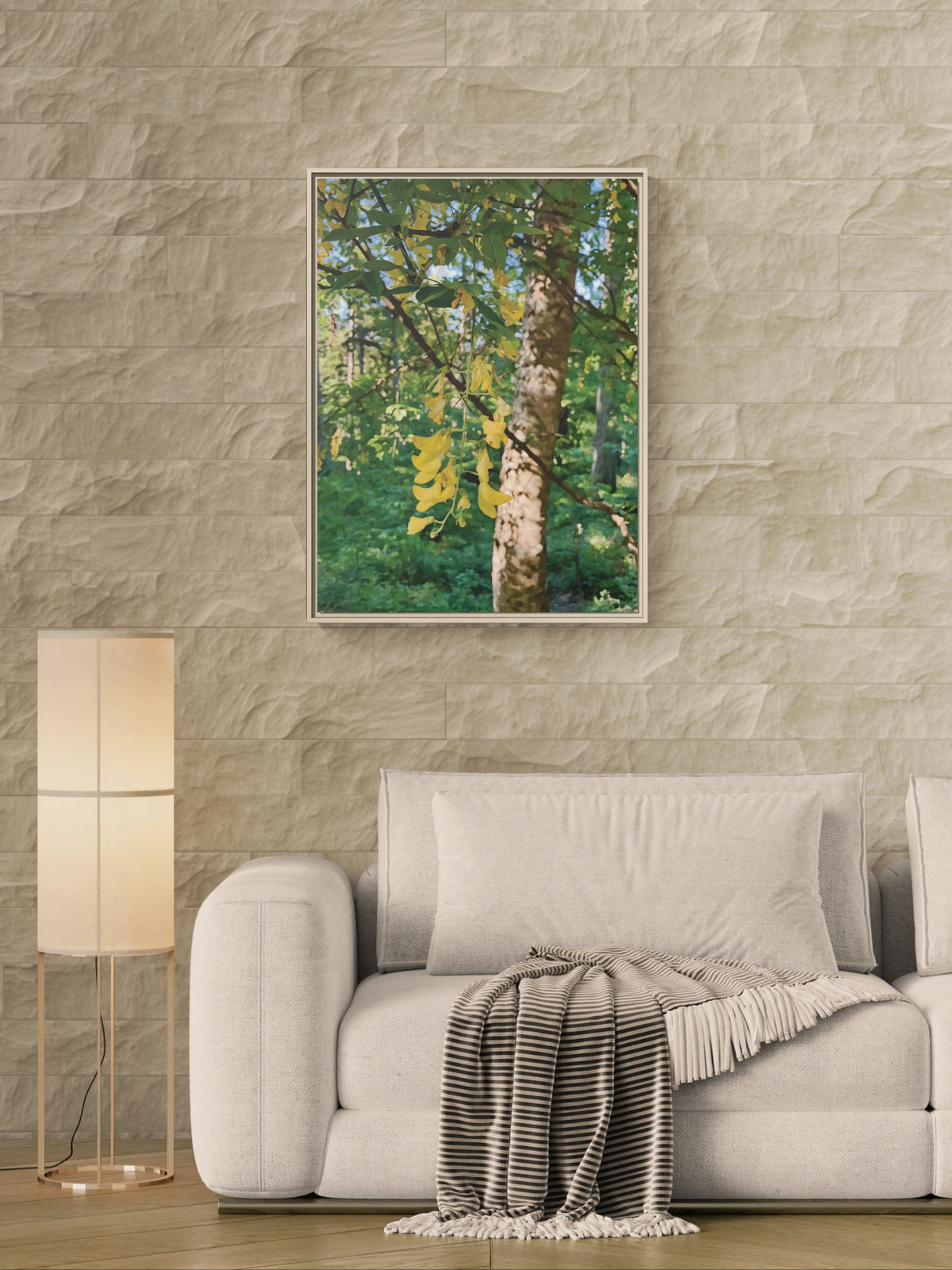 Framed canvas of yellow laburnum flowers hanging on a tree in a forest setting above a sofa