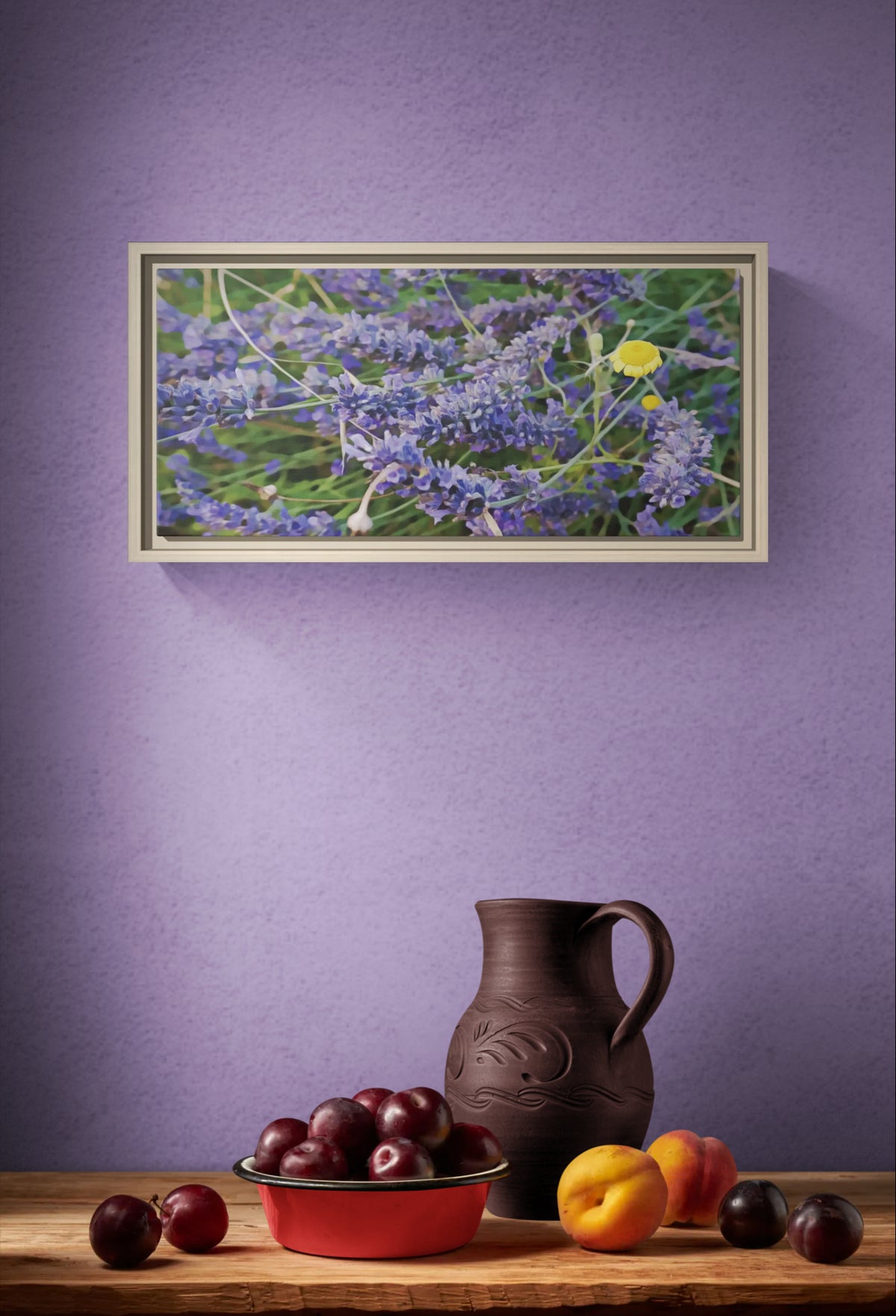 Framed lavender field print above a wooden table with a ceramic pitcher, bowl of plums, and fresh peaches