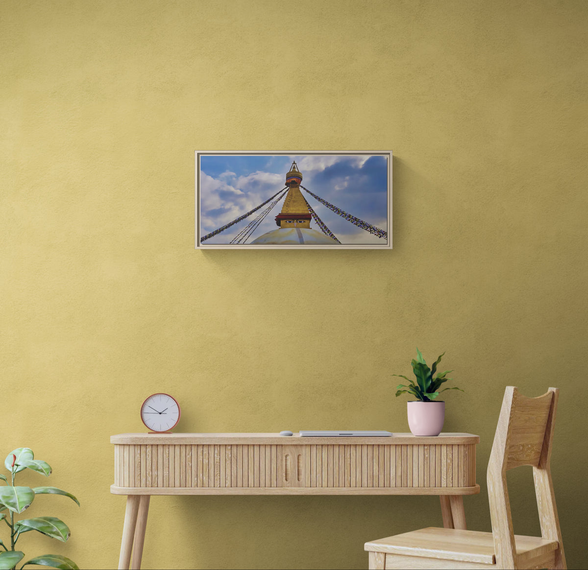 Framed wall art of Boudhanath Stupa with prayer flags hanging above a wooden desk