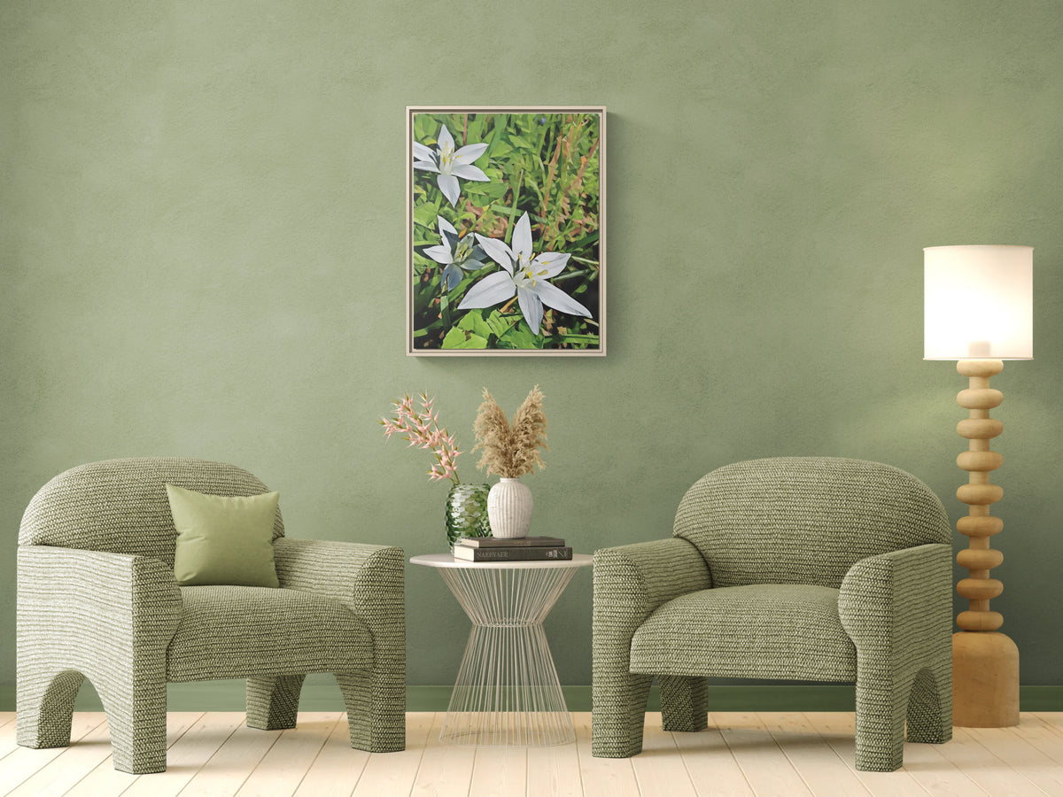 Framed floral wall art hanging above two green armchairs and a small side table