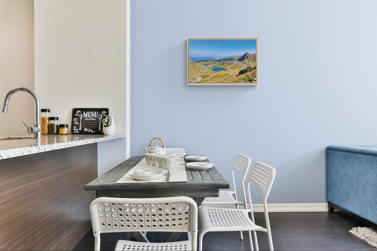 Framed mountain landscape print hanging on a light blue dining room wall