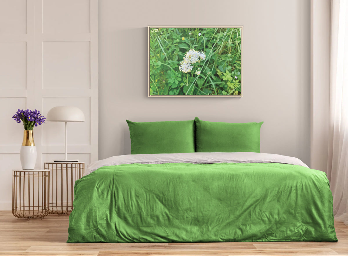 Green bedding set in a bedroom with a framed nature print on the wall