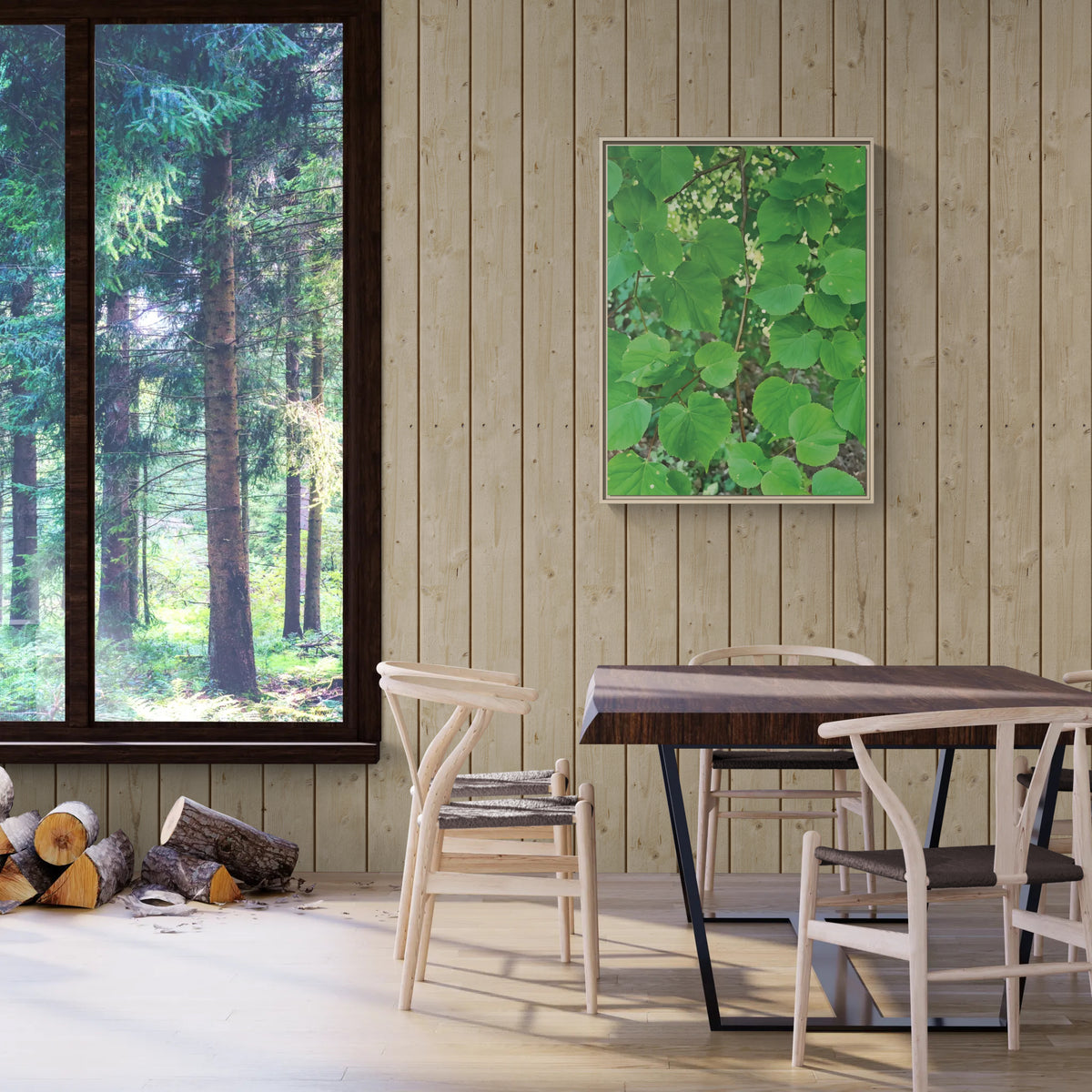 A framed green botanical art print featuring heart-shaped leaves, displayed on a light wood-paneled wall in a dining room setting with a wooden table and chairs.